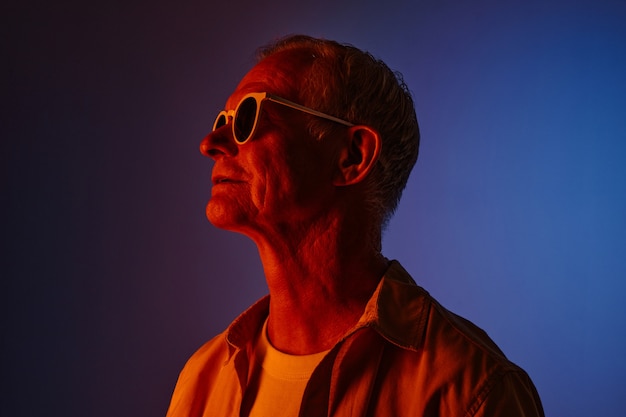 Colored portrait of modern senior man wearing sunglasses in red and blue, copy space