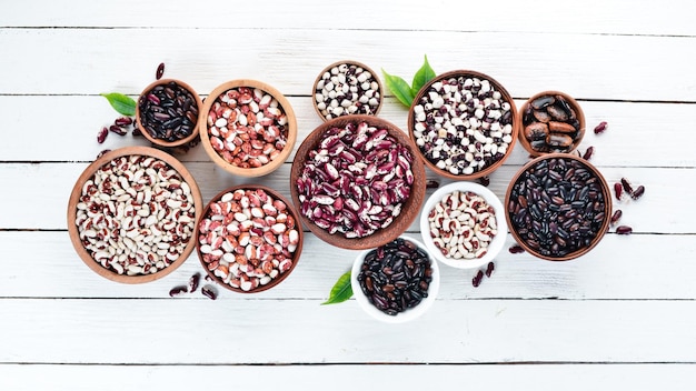 Colored raw beans in bowls on a white wooden table Top view Free copy space