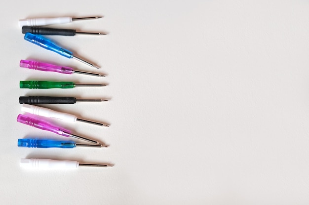 Colored screwdriver mini tools on the left frame on a white background