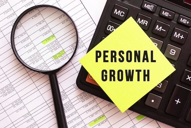 A colored sticker with the text PERSONAL GROWTH lies on the calculator Financial concept