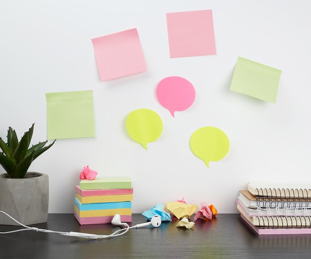 Colored stickers attached to a white wall, on the table a stack of notepads