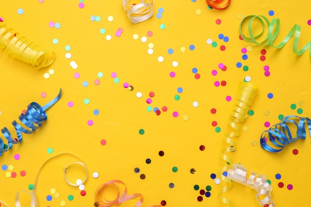 Colored streamer and confetti on yellow background Holiday birthday background