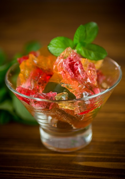 colored sweet fruit jelly in a glass glass on a wooden table