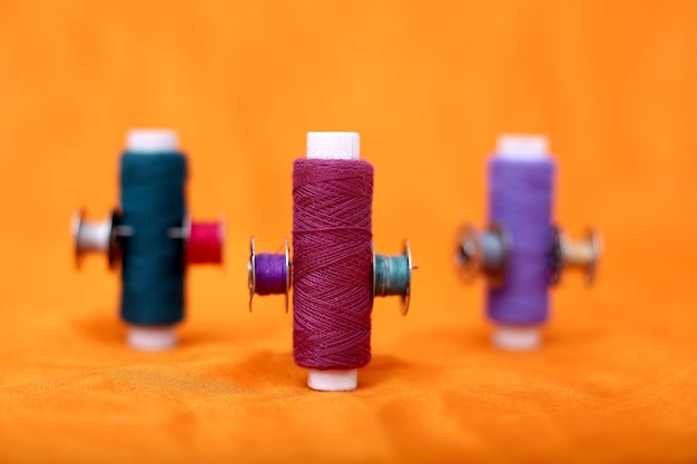 Colored threads with several bobbins on orange background