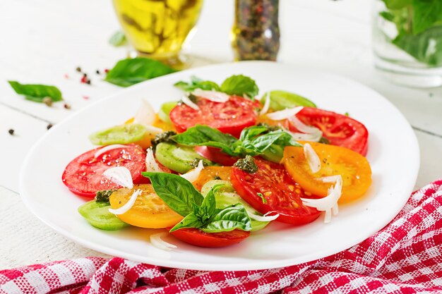 Colored tomato salad with onion and basil pesto. Vegan food.