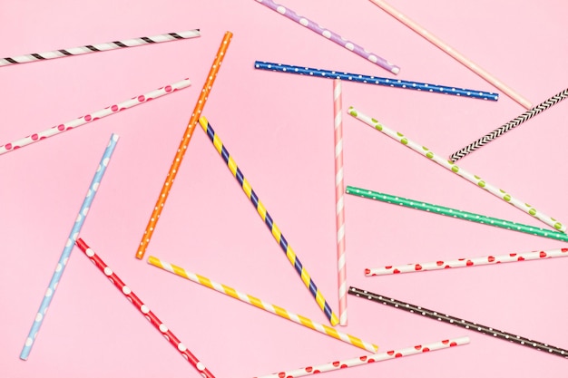 Colored with polka dots and striped drinking straws on a pink background with copy space