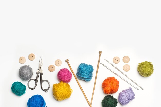 Colored wool spools and crochet hook on a wooden background with copy space