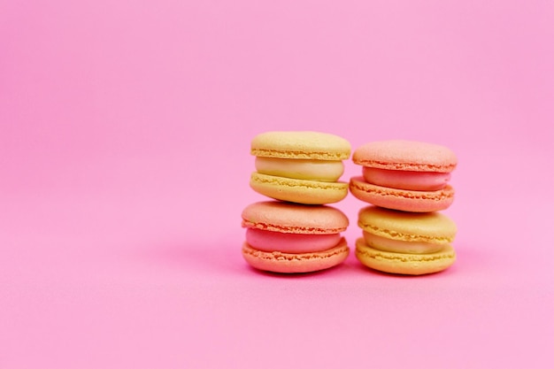 Colored yellow macaroons in pastel tones on a pink background