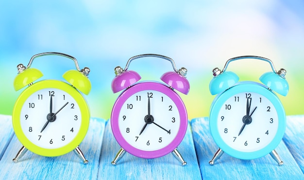 Colorful alarm clocks on table on blue background