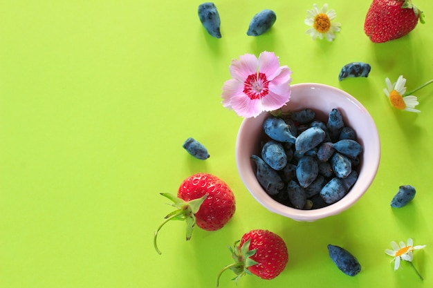 Colorful background with summer berries and flowers on green paper.