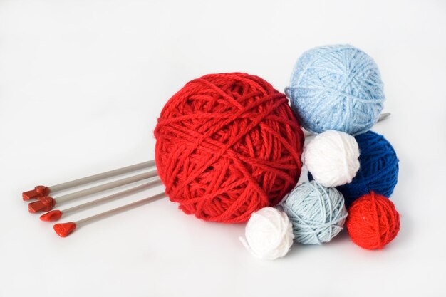 Colorful balls and needles for knitting lying on a white background