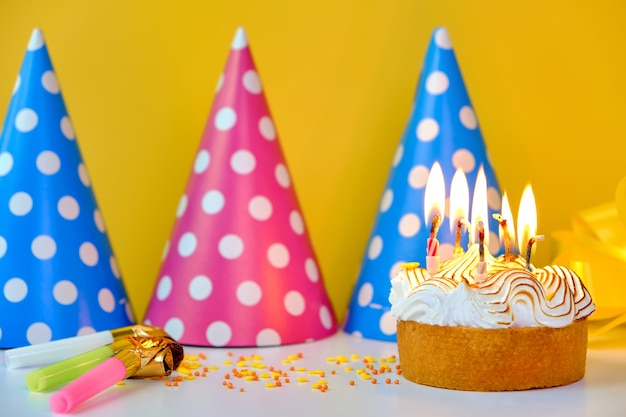 A colorful birthday cake with candles and confetti on a yellow background