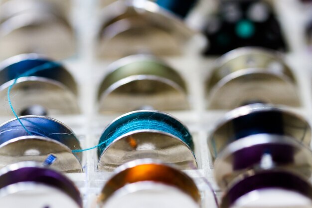 Colorful bobbins of thread in bobbin box in tailor shop.