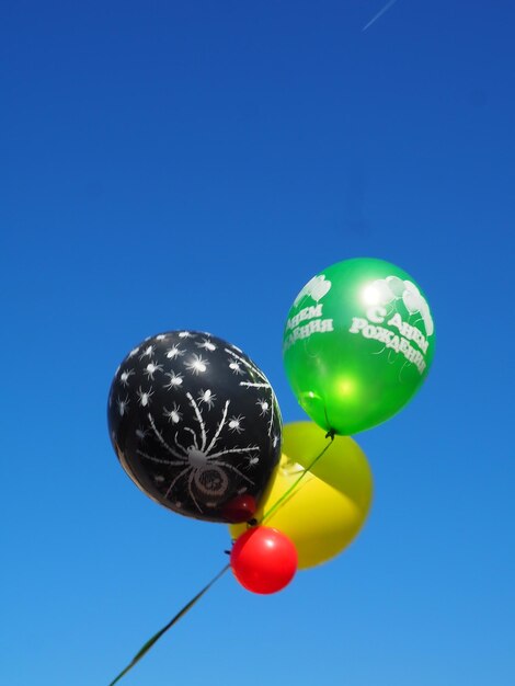 Colorful bouncing balls outdoors against blue sunny sky