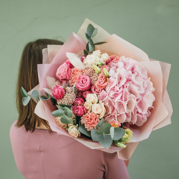 Colorful bouquet of different fresh flowers in the hands of a florist woman Rustic flower background