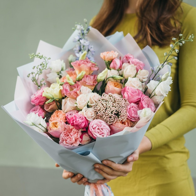 Colorful bouquet of different fresh flowers in the hands of a florist woman Rustic flower background