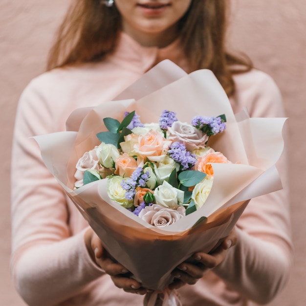 Colorful bouquet of different fresh flowers in the hands of a florist woman