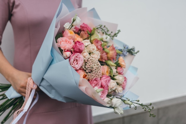 Colorful bouquet of different fresh flowers in the hands of a florist woman