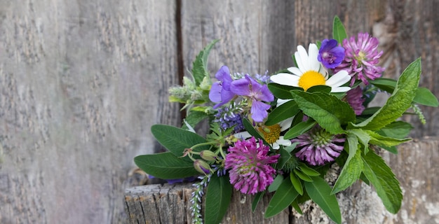 Colorful bouquet of meadow flowers on a wooden background with a place for text Postcard