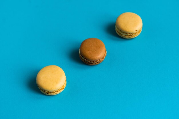 Colorful cake macaron or macaroon on blue background flat lay top view copy space