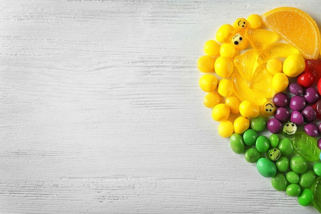 Colorful candies arranged as semi heart on light background