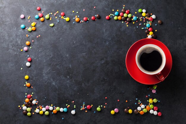 Colorful candies and coffee cup on stone background