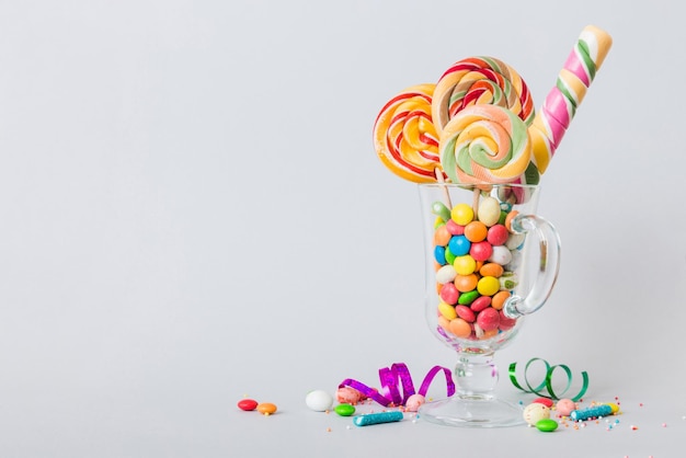 Colorful candies in cup on table on light background background Large swirled lollipops Creative concept of a jar full of delicious sweets from the candy store