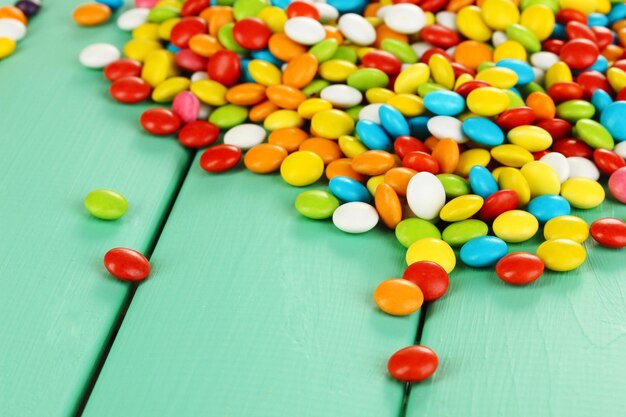 Colorful candies on green wooden background