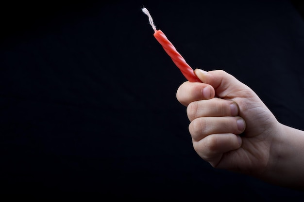 Colorful candle in hand on a black background