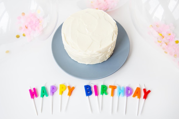 Colorful candles with Happy Birthday lettering isolated on white background along with confetti and bento cake Holiday and surprise concept