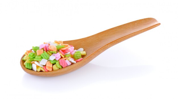 Colorful candy in wood spoon on white wall