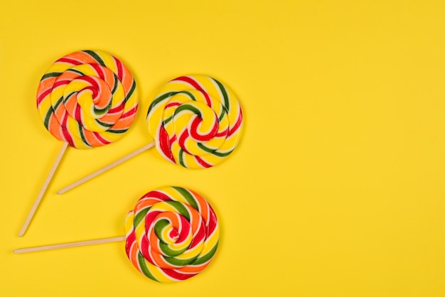 Colorful candy on a yellow  background. Lollipop. Top view. Copy space.