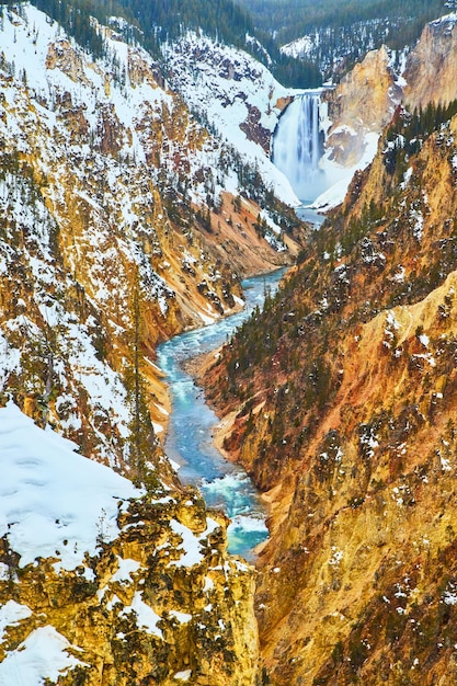 Colorful canyons with Yellowstone Upper Falls with snowy cliffs