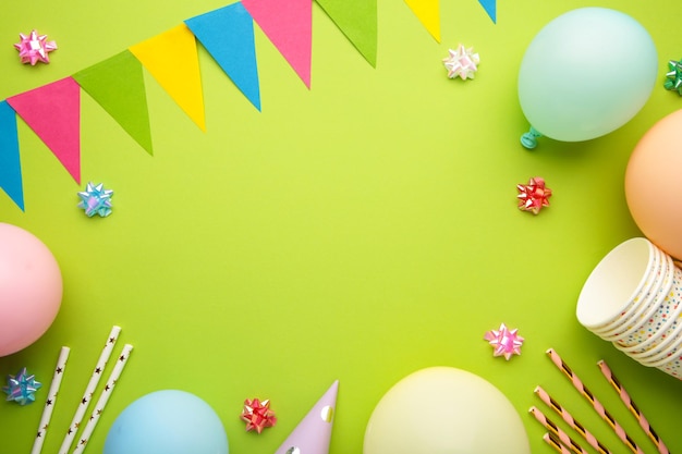 Colorful carnival or party frame of balloons streamers and confetti on green background Space for text