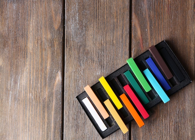 Colorful chalk pastels in box on wooden background