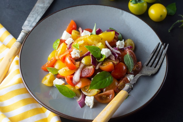 Colorful cherry tomatoes and basil salad on a plate. Healthy, summer food.