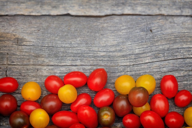 Colorful cherry tomatoes on wooden surface with copyspace