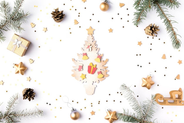 Colorful Christmas tree with New Year`s decorations on white background. Red gift box, candies, gold stars on Holiday card. Flat lay, top view