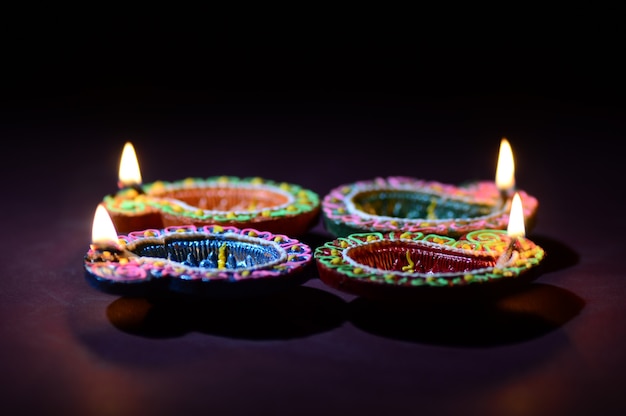 Colorful clay Diya lamps lit during Diwali celebration. Greetings Card Design Indian Hindu Light Festival called Diwali.