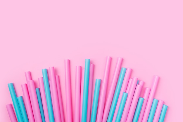 Colorful cocktail tubes lie on a bright pink background. Top view.