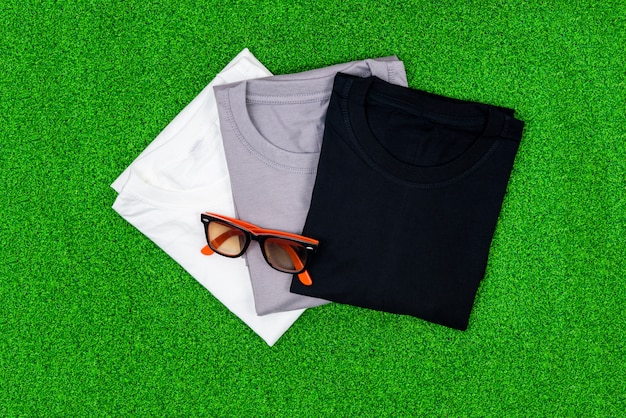 Colorful of cotton T shirt with sun glasses on green grass.