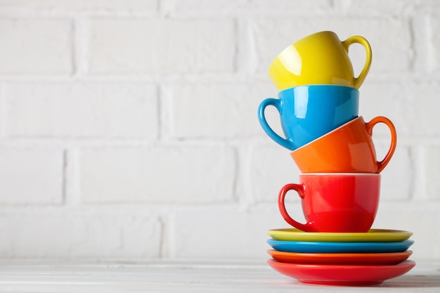 Colorful cups on the white of a brick wall. with copy space. Horizontal. Selective focus.