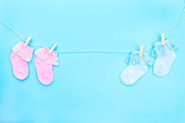 Colorful cute baby socks hanging on the clothesline on blue background Baby accessories Flat lay