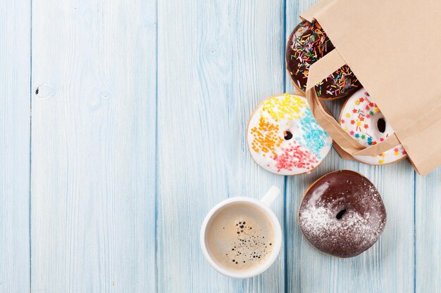 Colorful donuts in paper bag and coffee cup