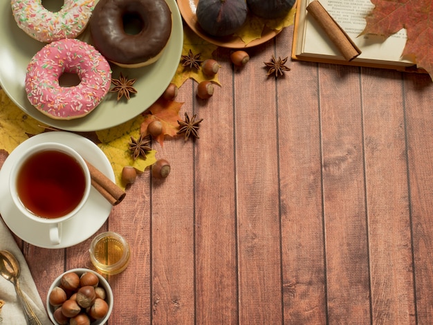 Colorful donuts on plate autumn and a Cup of tea on rustic wooden surface