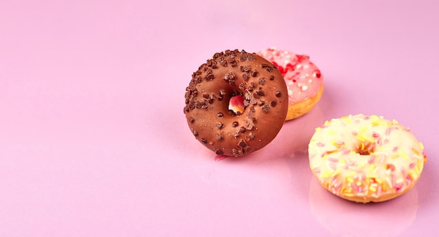 Colorful donuts on purple background Copy space