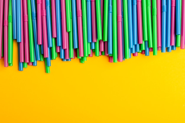 Colorful drinking straws on a yellow background. Copy space for text.