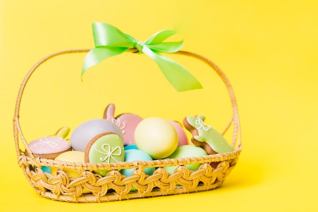 Colorful easter cookies in basket with Multi colors Easter eggs on colored background Pastel color Easter eggs holiday concept with copy space