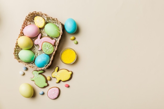 Colorful easter cookies in basket with Multi colors Easter eggs on colored background Pastel color Easter eggs holiday concept with copy space