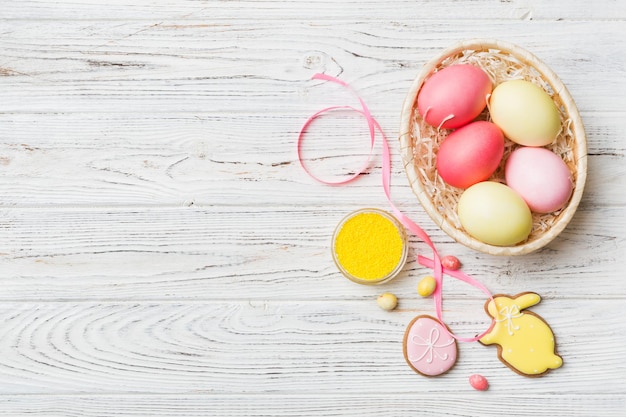 Colorful easter cookies in basket with Multi colors Easter eggs on colored background Pastel color Easter eggs holiday concept with copy space